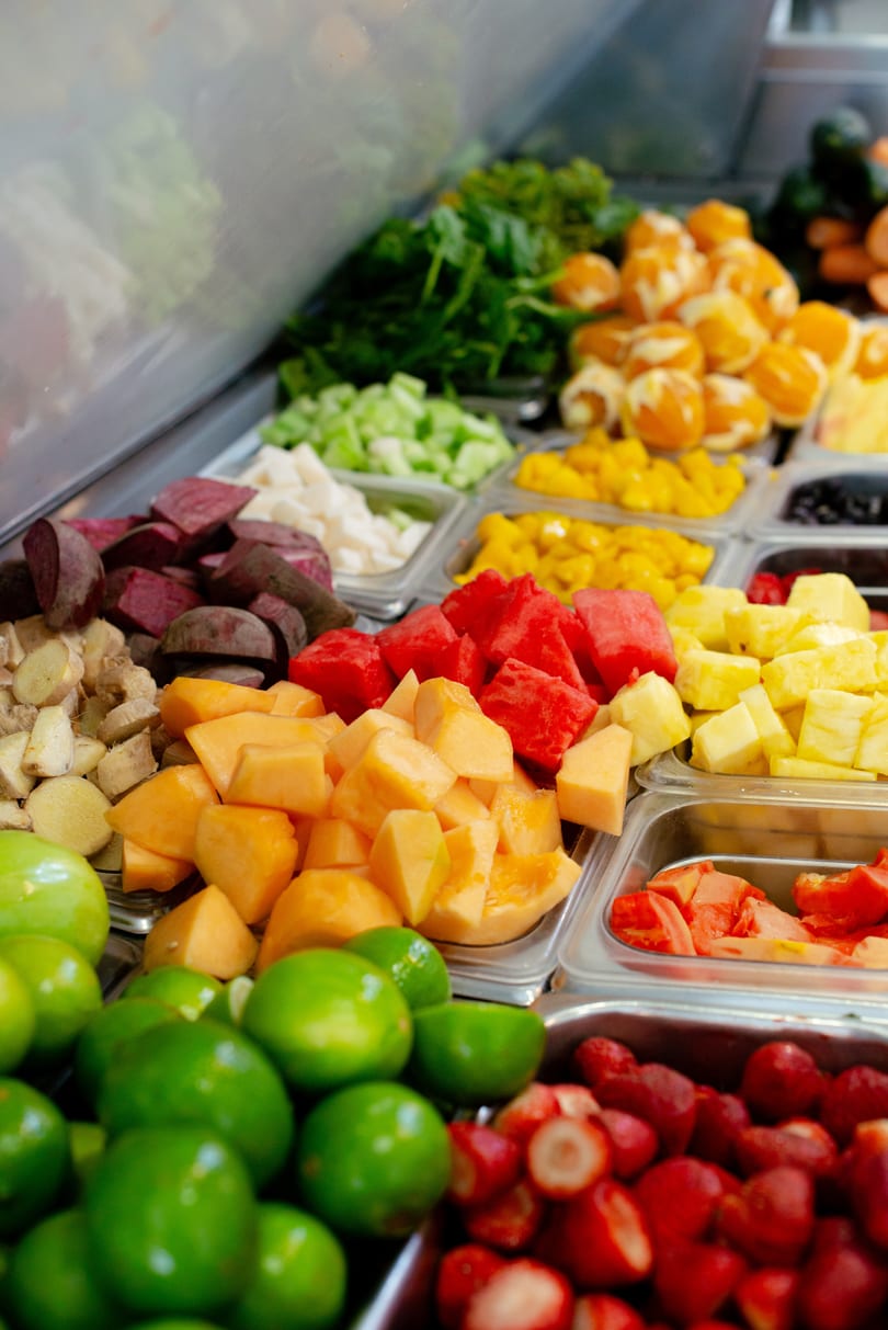 A vibrant buffet of fresh-cut fruits and vegetables, including watermelon, cantaloupe, and limes.